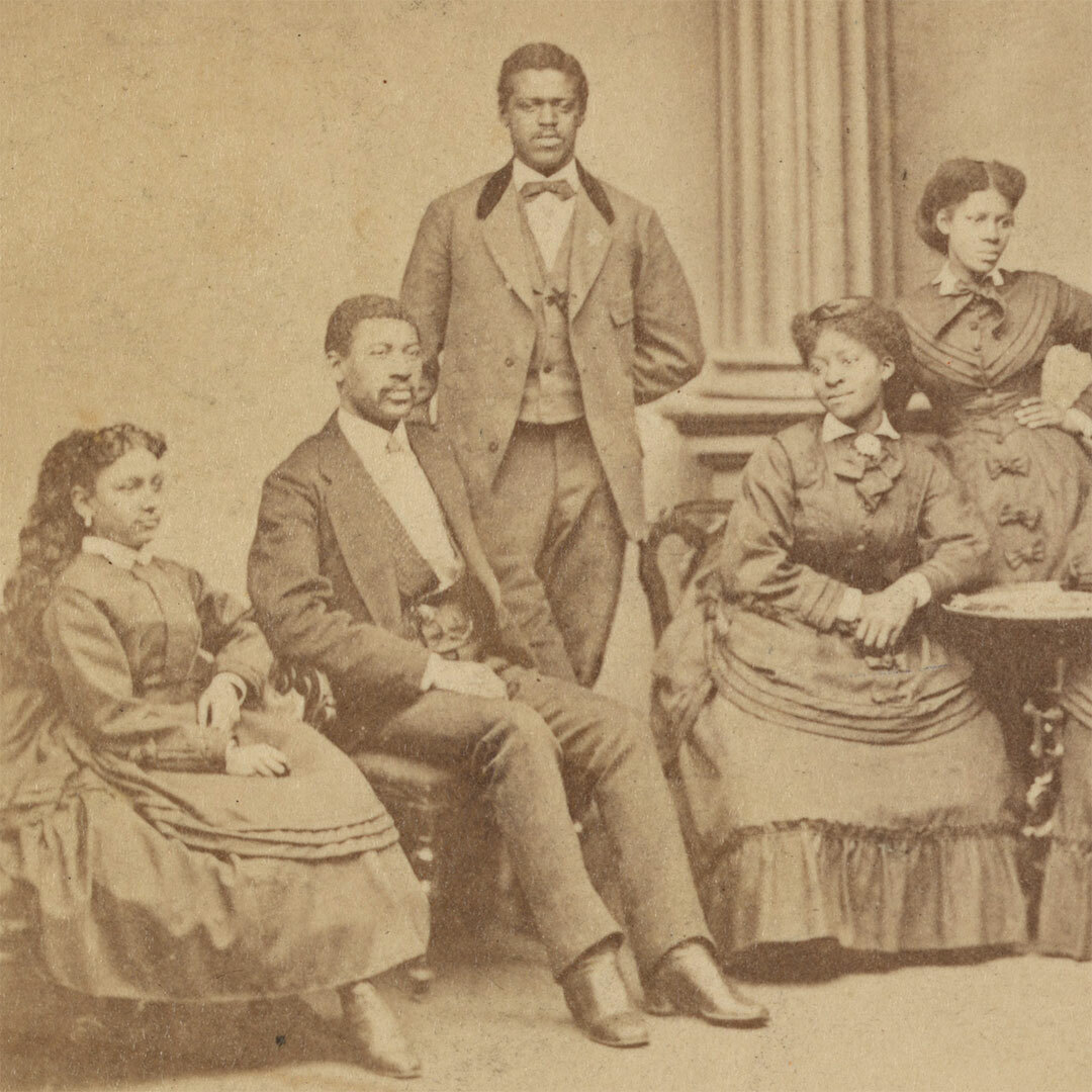 Vintage photo of a group of Black men and women seated and standing, wearing late 19th-century clothing.