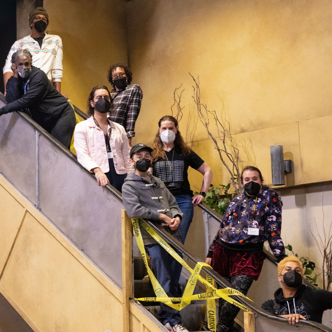 The cast and select creative team members of Hedwig posing on the set's escalator.