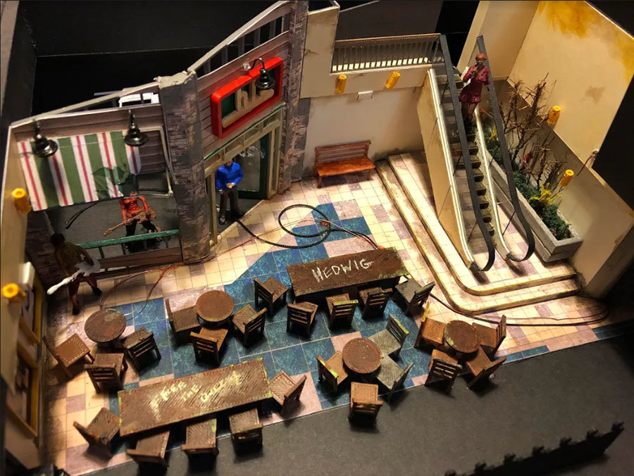 Design model of the Hedwig set, showing the façade of a defunct mall Chili's with tables and chairs at left/center and escalator at right.