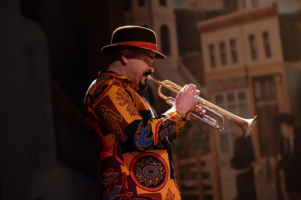 A man plays a trumpet in a dramatic light.