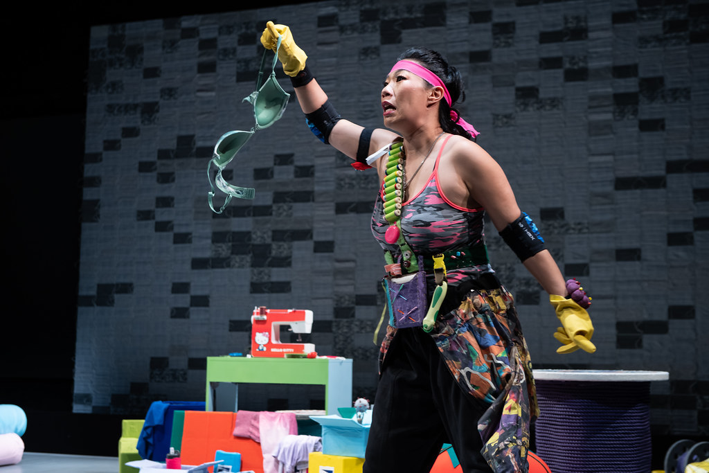 A woman holds a camo bra in her hand and speaks.