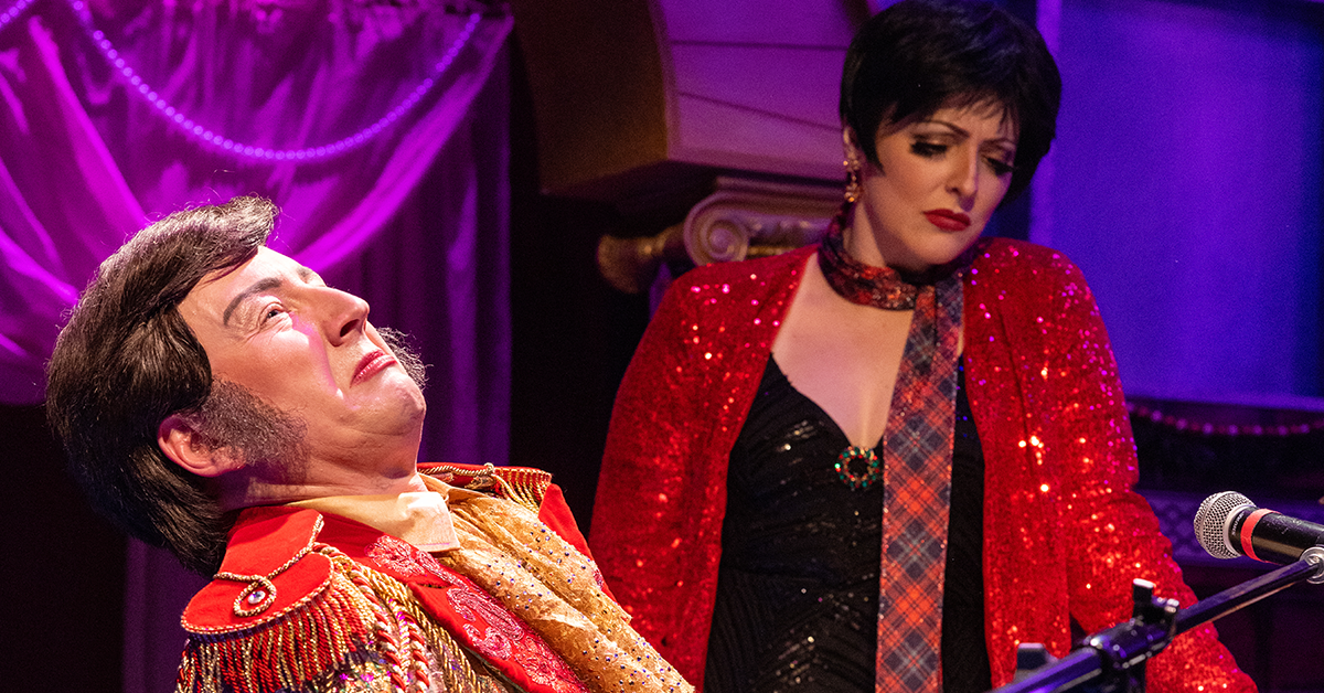 A man seated at a piano leans back dramatically in the spotlight as a woman in a red sequined top looks down thoughtfully.