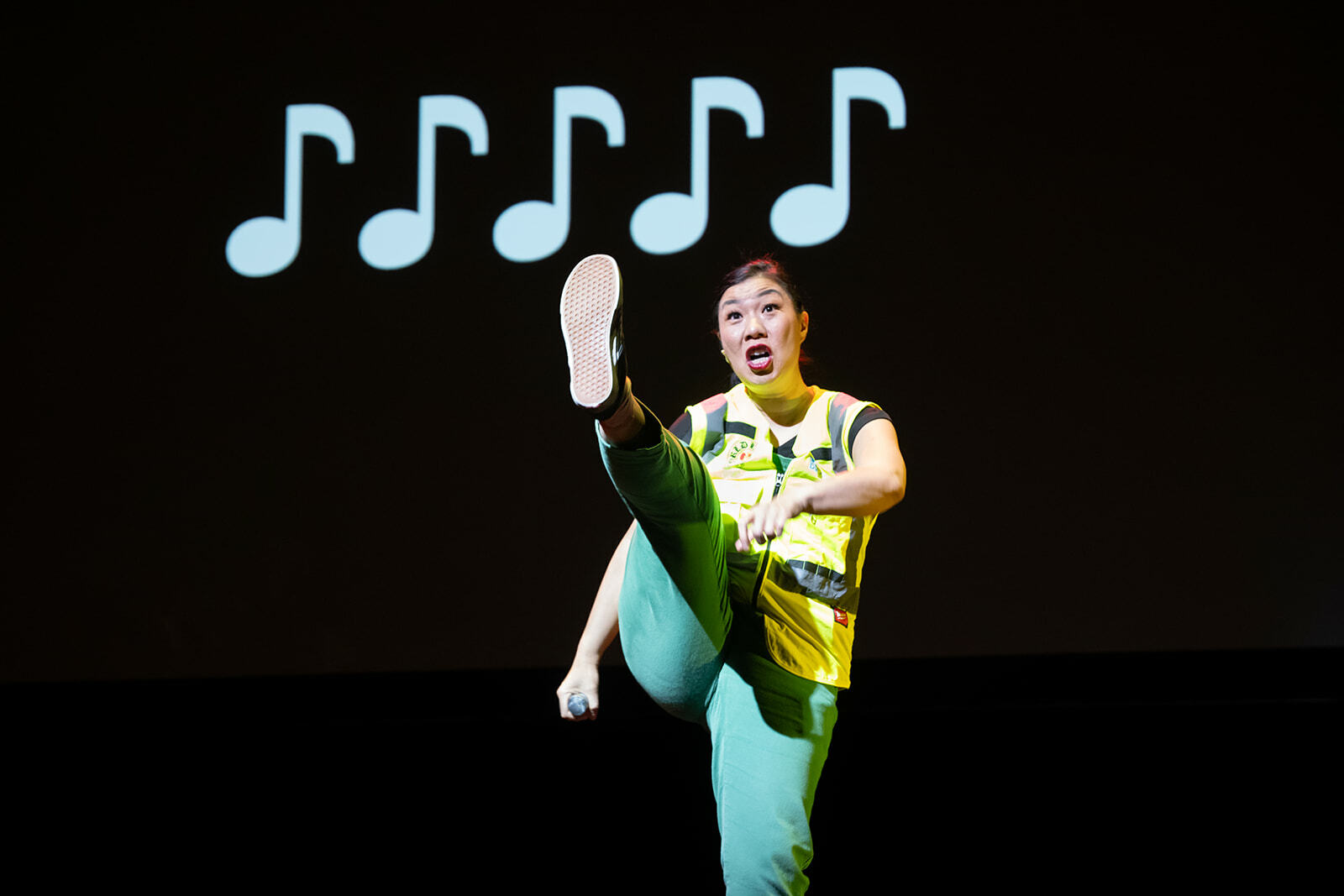 Kristina Wong high kicking in front of musical notes