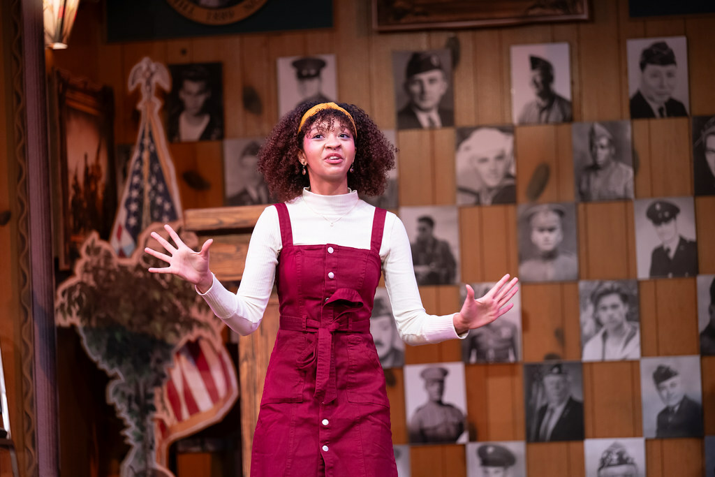 A young woman stands gesturing, as if making a compelling argument.