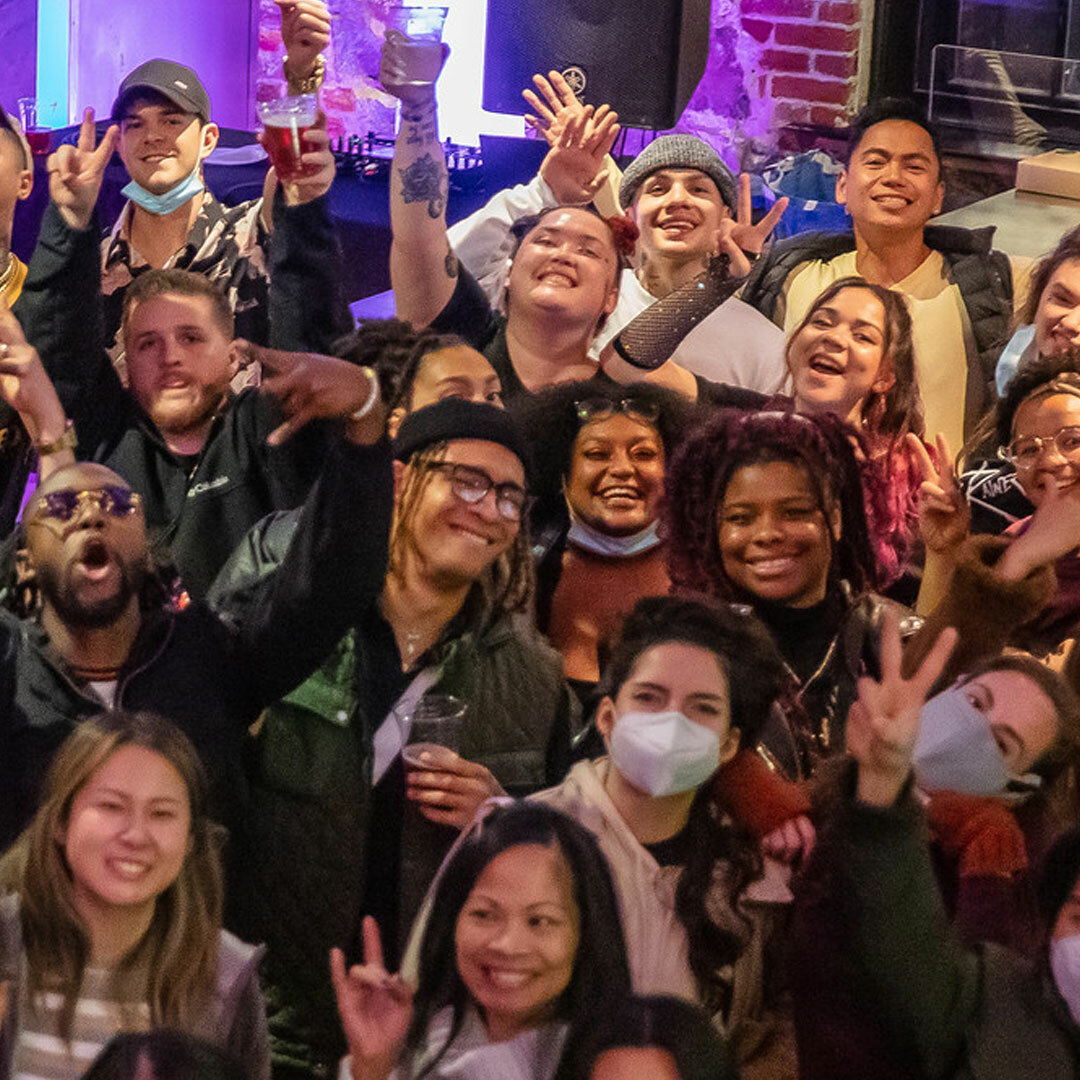 A crowd of smiling people attending an event in The Armory lobby.