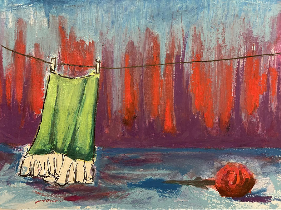 Frida's green skirt is hanging by itself before a blue, orange, and purple background. A red flower lies on the stage. in the foreground.