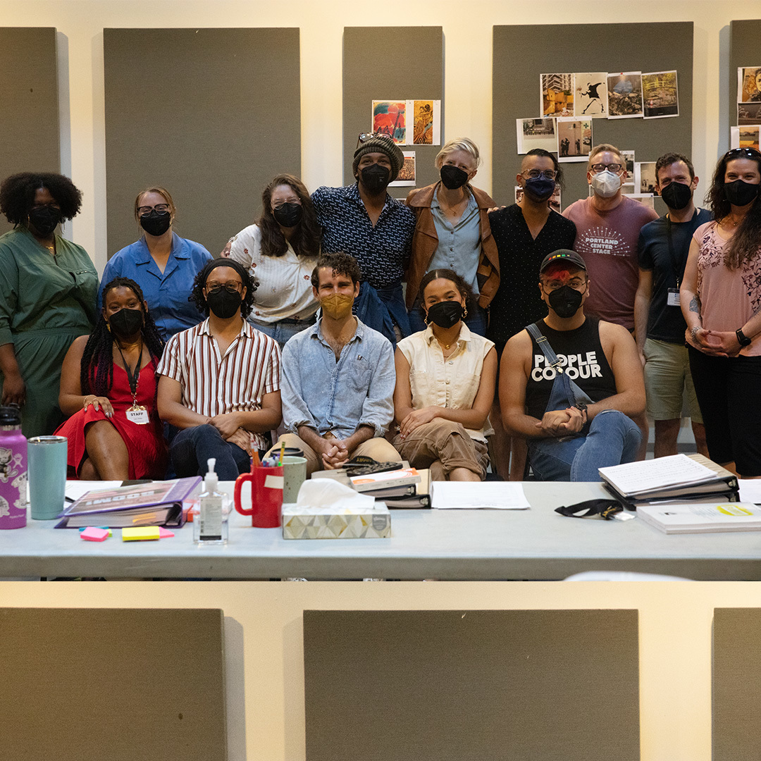 A group of 14 people gathered closely together, wearing masks.